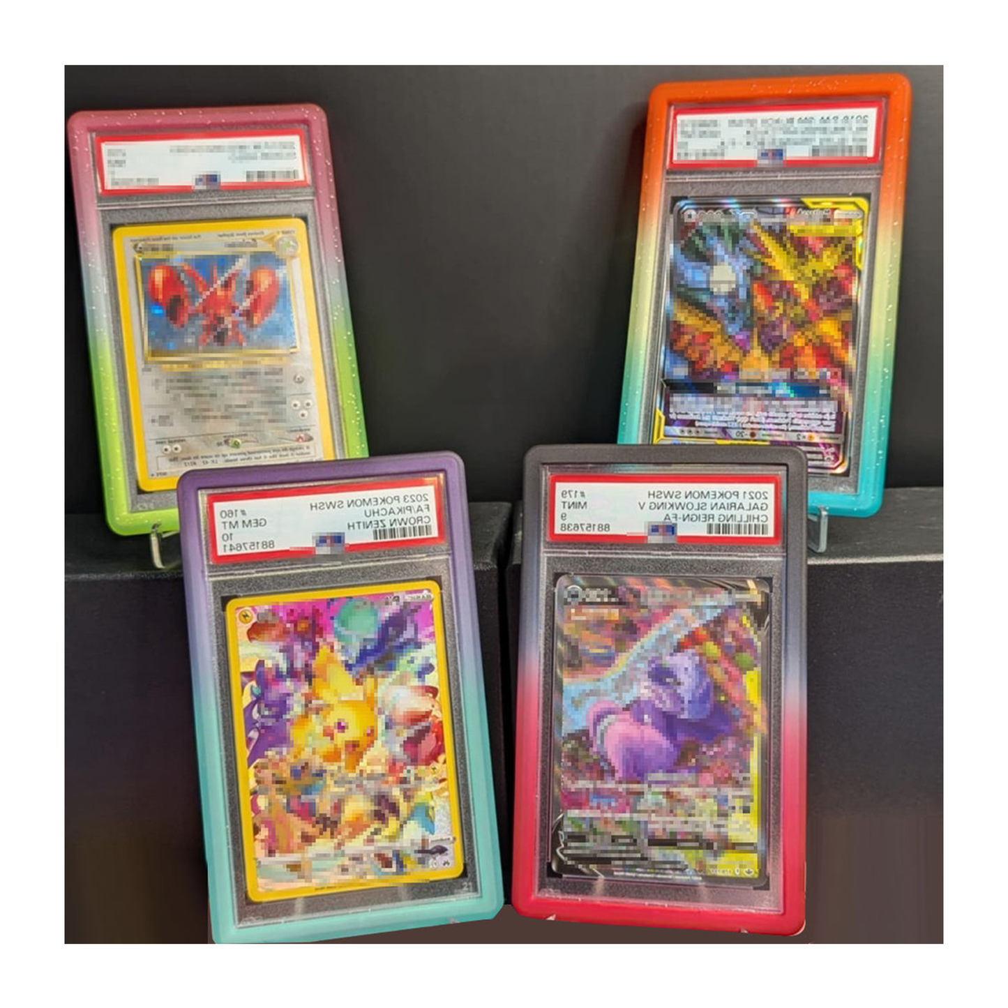 Four trading cards in protective cases with visible grading labels on a dark background