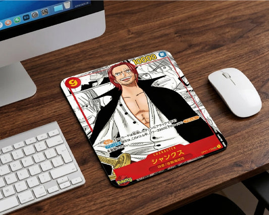 Close-up of Red-Haired Shanks anime mouse pad designed like a collectible trading card, placed on wooden desktop beside wireless mouse and modern computer setup