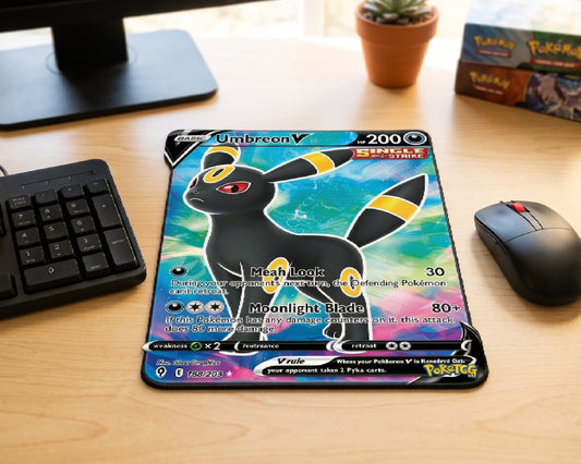 Umbreon V Pokémon themed mouse pad displayed on a modern wooden desk with compact keyboard, wireless mouse, monitor stand, Pokémon booster boxes, and small indoor plant