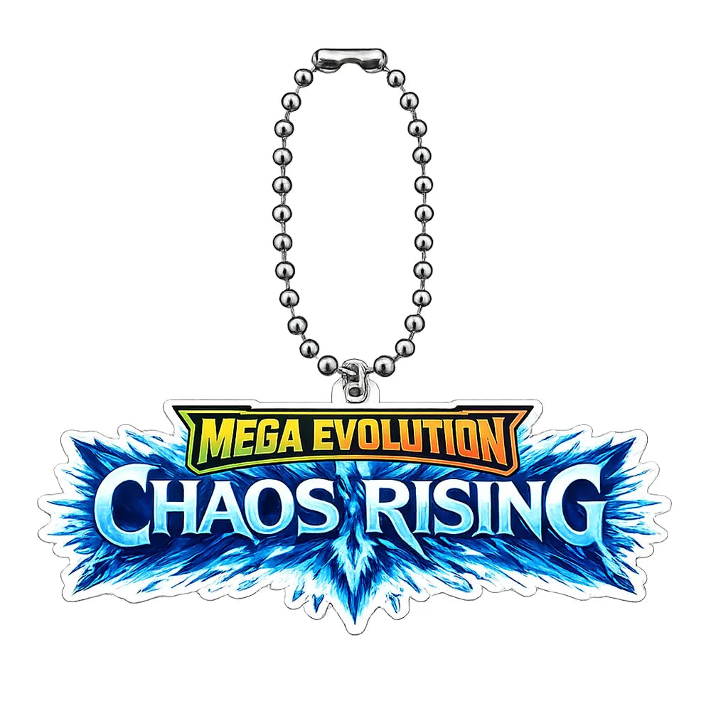 A Mega Evolution Perfect Order keychain with a silver clasp, resting on a wooden desk next to a keyboard, notebook, and plant.