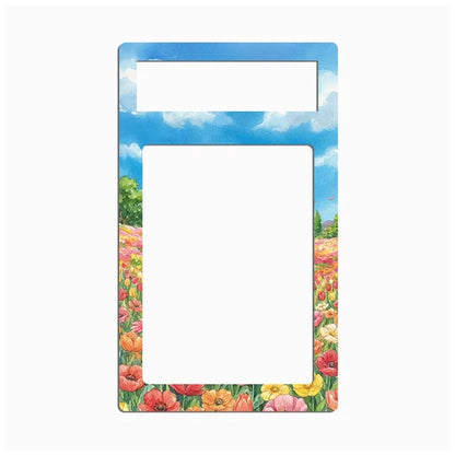 A rectangular picture frame with a colorful border depicting a blue sky with clouds and a field of pink, red, orange, and yellow flowers, shown on a plain white background.