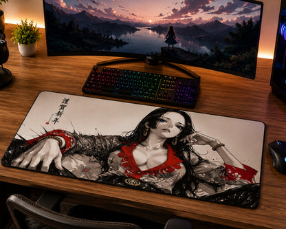A large rectangular gaming desk mat featuring an anime-style illustration of a woman in a red and black outfit, placed on a wooden desk in front of a curved monitor, keyboard, and mouse.