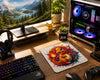 A styled desktop setup with a large printed mousepad featuring colorful cartoon creatures on a white background, placed on a wooden desk alongside a keyboard, mouse, headphones, monitor, and a PC tower with illuminated fans.