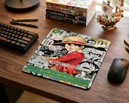 Close-up of Monkey D. Luffy manga collage mouse pad with Japanese text design, placed on wooden desk beside mechanical keyboard, gaming mouse, manga books, and Thousand Sunny model