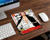 Close-up of Red-Haired Shanks anime mouse pad designed like a collectible trading card, placed on wooden desktop beside wireless mouse and modern computer setup