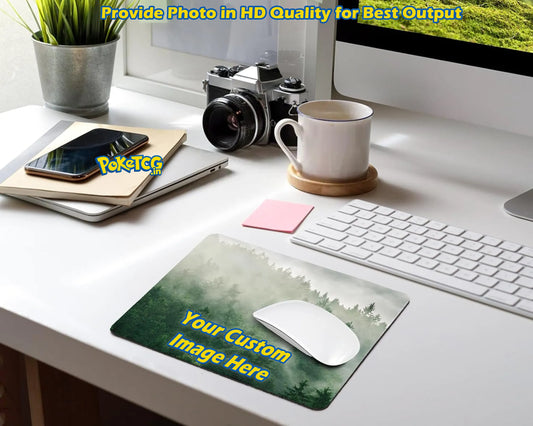A custom desk mat with a green forest landscape print and yellow placeholder text, shown on a white desk alongside a keyboard, mouse, camera, laptop, and mug. The desk mat has a 'PokettoG' watermark overlay.