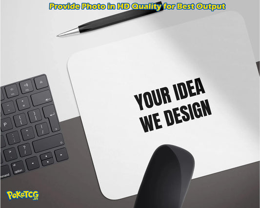 A white rectangular mockup pad or sign on a desk with the text 'YOUR IDEA WE DESIGN' in bold black letters. A black pen rests above it, with part of a keyboard on the left and a black object in the foreground.