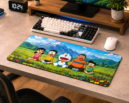 A large rectangular desk mat featuring a colorful cartoon scene with Doraemon, children, mountains, and flowers, shown on a beige desk alongside a keyboard, mouse, monitor stand, and chair.