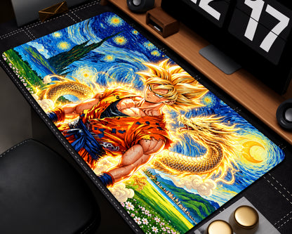 A rectangular desk mat featuring a colorful anime-style print of Goku in an orange gi against a swirling blue and yellow Starry Night-inspired sky, with a dragon motif. The mat is shown laid out on a desk near a monitor and keyboard.