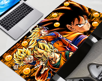A large desk mat featuring a colorful Dragon Ball Z anime print with Goku, Vegeta, and Son Goku, styled on a desk next to a laptop and keyboard.