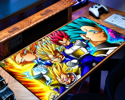 Dragon Ball Z Vegeta extended gaming mouse pad featuring multiple Saiyan warrior illustrations in blue and white armor, golden and red spiky hair, and vibrant yellow, turquoise, and blue energy effects, displayed on a wooden gaming desk.