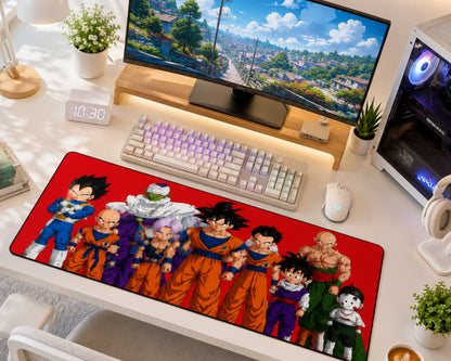 A large desk mat featuring characters from Dragon Ball Z on a red background, styled on a white desk alongside a keyboard, mouse, monitor, and plants.