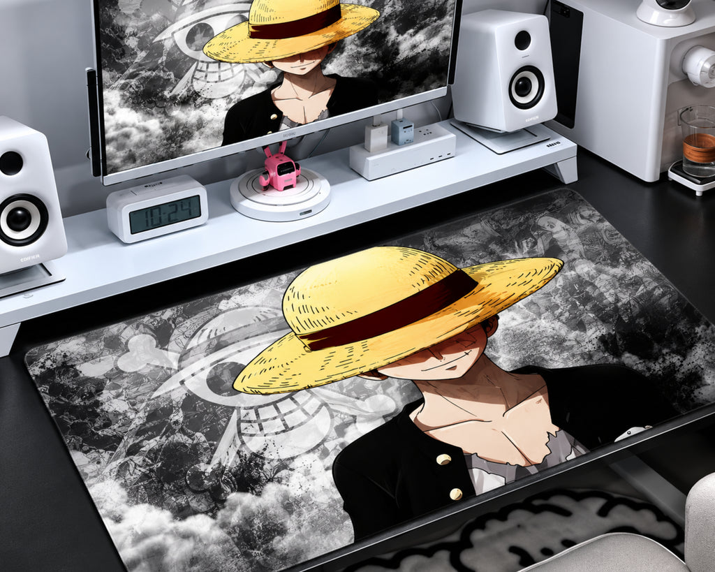 Luffy-inspired One Piece gaming mouse pad featuring a golden straw hat with a dark red band, a black outfit, a grayscale manga collage, and a large monochrome pirate skull emblem.