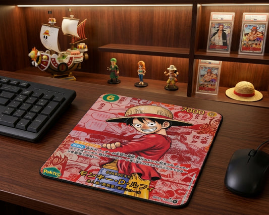 Monkey D. Luffy anime trading card style mouse pad displayed on a premium wooden desk with One Piece collectibles, figurines, graded cards, and gaming setup decor
