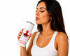 A woman with dark hair wearing a white ribbed tank top is shown from the chest up, drinking from a white tumbler with a clear straw. The tumbler features a red and black Spider-Man graphic and a red Marvel logo near the bottom.
