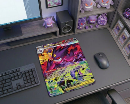 Top-angle gaming desk featuring Mega Gengar Pokémon card mouse pad, wireless mouse, compact keyboard, collectible Pokémon cards, and purple Gengar themed decorations
