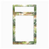 A rectangular decorative frame or magnet with a watercolor-style nature border featuring green grass, gray rocks, and brown earth, with two blank white cutout areas near the top.