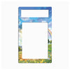 A rectangular decorative frame or magnet with rounded corners, featuring a colorful landscape print of a blue sky, white clouds, a rainbow, green grass, and yellow wildflowers. The top portion has a smaller blank white rectangle, and the lower portion has a larger blank white rectangle.