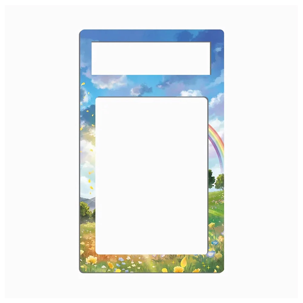 A rectangular decorative frame or magnet with rounded corners, featuring a colorful landscape print of a blue sky, white clouds, a rainbow, green grass, and yellow wildflowers. The top portion has a smaller blank white rectangle, and the lower portion has a larger blank white rectangle.