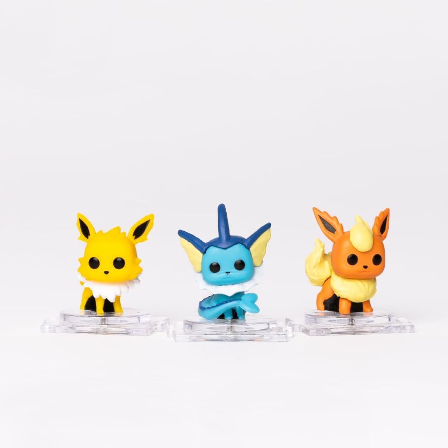 Three colorful figurines on clear stands against a white background
