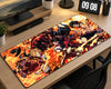 A large rectangular desk mat with a vibrant anime-style illustration of characters surrounded by flames, shown on a light wood desk in a home office setting.