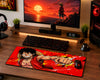 A large desk mat featuring a vibrant anime-style illustration of a character in a red outfit against a red and orange burst background, styled on a wooden desk next to a keyboard, mouse, and computer setup.