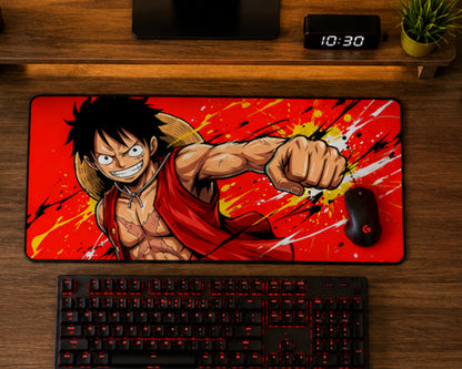 A large rectangular desk mat featuring an anime character on a red splattered background, styled on a wooden desk above a keyboard and mouse.