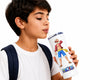 A young boy with a white t-shirt and dark backpack strap drinking from a white insulated tumbler with a straw. The tumbler features a colorful illustration of the character Monkey D.