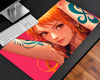 Nami-inspired One Piece anime gaming mouse pad featuring a close-up orange-haired character with brown eyes, a teal shoulder tattoo, gold earrings, and a vibrant hot-pink and orange background.