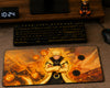 A large rectangular gaming mousepad featuring an anime character with crossed arms in a black and orange outfit against a fiery orange background, styled on a desk with a keyboard, mouse, and a small figurine.