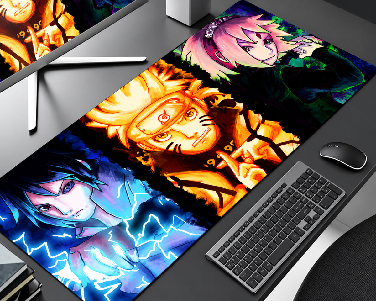 Naruto Shippuden extended anime gaming mouse pad featuring Naruto Uzumaki in glowing golden-orange chakra artwork at the center, Sasuke Uchiha surrounded by electric blue lightning at the bottom, and pink-haired Sakura Haruno in a dark colorful panel at the top, displayed on a gray computer desk beside a black keyboard and mouse.
