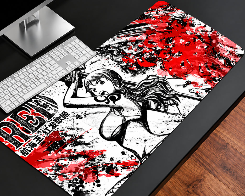 A large desk mat with a bold anime-style illustration and red, black, and white paint-splatter design, shown on a dark desk next to a keyboard and monitor stand.