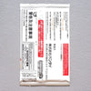 A single white rectangular product packet with dense black Japanese text and red warning panels, photographed flat against a light gray textured background.