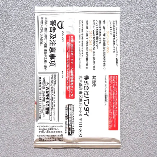 A single white rectangular product packet with dense black Japanese text and red warning panels, photographed flat against a light gray textured background.