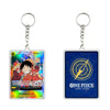 Two acrylic keychains representing the One Piece Card Game, showing the front holographic card design of Monkey D. Luffy and the back blue card with a gold compass graphic and 'ONE PIECE CARD GAME' text.