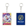 Two One Piece Card Game acrylic keychains shown side by side on a plain white background. The left keychain features a colorful character illustration with the text 'AFARO' and '12000 JT', while the right keychain has a dark blue background with a gold compass design and the text 'ONE PIECE CARD GAME'.