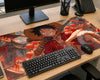 A large anime desk mat featuring characters from One Piece, styled on a light wood desk alongside a keyboard, mouse, monitor, and phone.