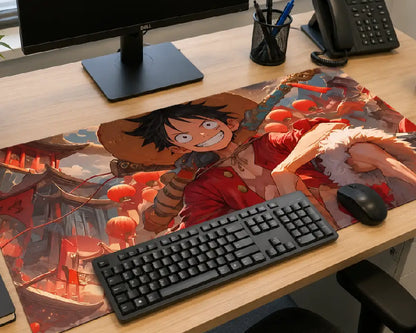 A large anime desk mat featuring characters from One Piece, styled on a light wood desk alongside a keyboard, mouse, monitor, and phone.