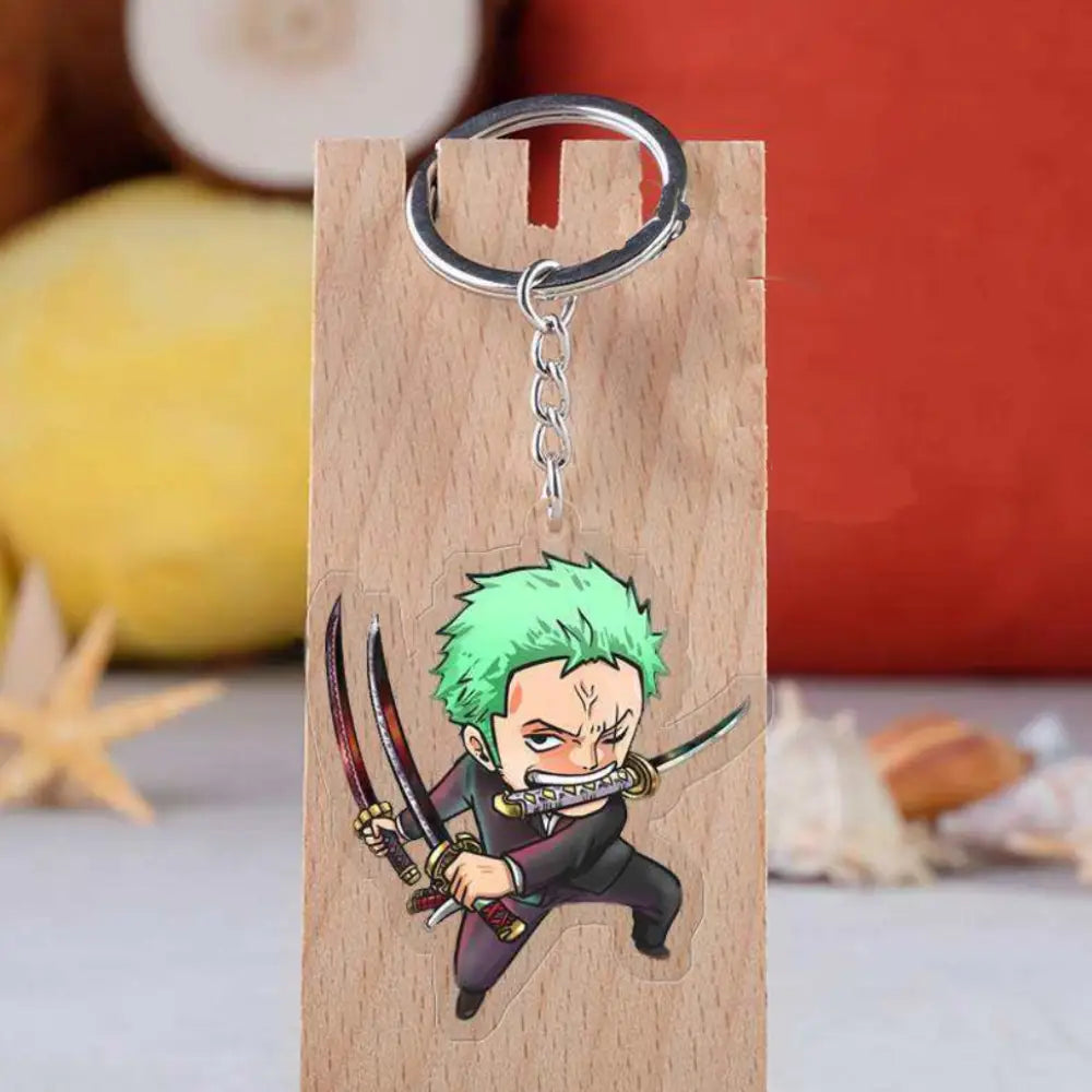 A chibi anime keychain featuring a character with bright green hair and a sword, attached to a silver metal key ring and displayed on a wooden backing card.