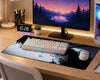 A gaming desk setup featuring a large black and white wolf print desk mat with a white mechanical keyboard and a white Logitech gaming mouse on top, set on a light wood desk under a computer monitor.