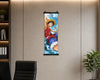 A vertical anime wall scroll featuring Monkey D. Luffy from One Piece, displayed on a beige paneled wall in an office setting with a desk chair and plant visible.