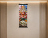 A colorful vertical wall scroll artwork hanging on a beige wall with slatted wood panels on both sides. The artwork depicts a stylized figure seated on a rock with bright abstract and geometric elements in pink, blue, yellow, green, and orange tones.