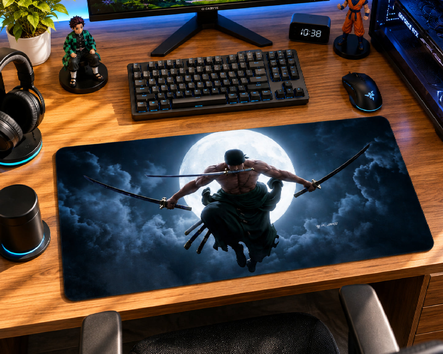 A large rectangular desk mat featuring a graphic print of a samurai flying against a full moon, displayed on a wooden gaming desk with a keyboard, mouse, headphones, and other desk accessories.