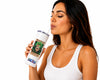 A woman in a white ribbed tank top holds a white insulated tumbler with a straw. The tumbler features a colorful 'Wanted' poster-style graphic with a cartoon character and the text 'WANTED' and 'JACKSON HOLE, PA'.