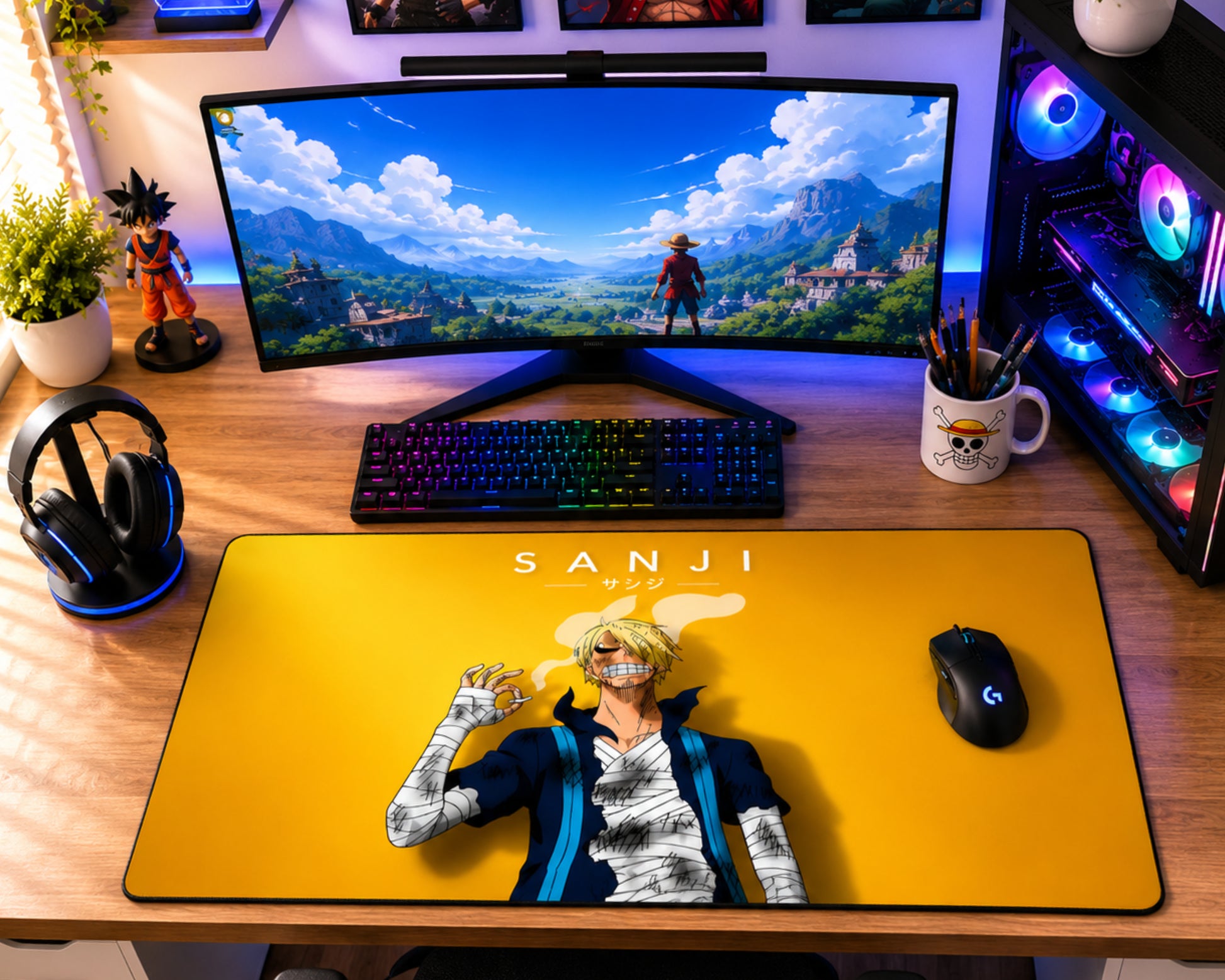 A large yellow gaming desk mat featuring an anime character print and the word 'SANJI' is laid out on a wooden desk. The setup includes a curved monitor, RGB mechanical keyboard, mouse, headphones, and a PC tower with illuminated fans.