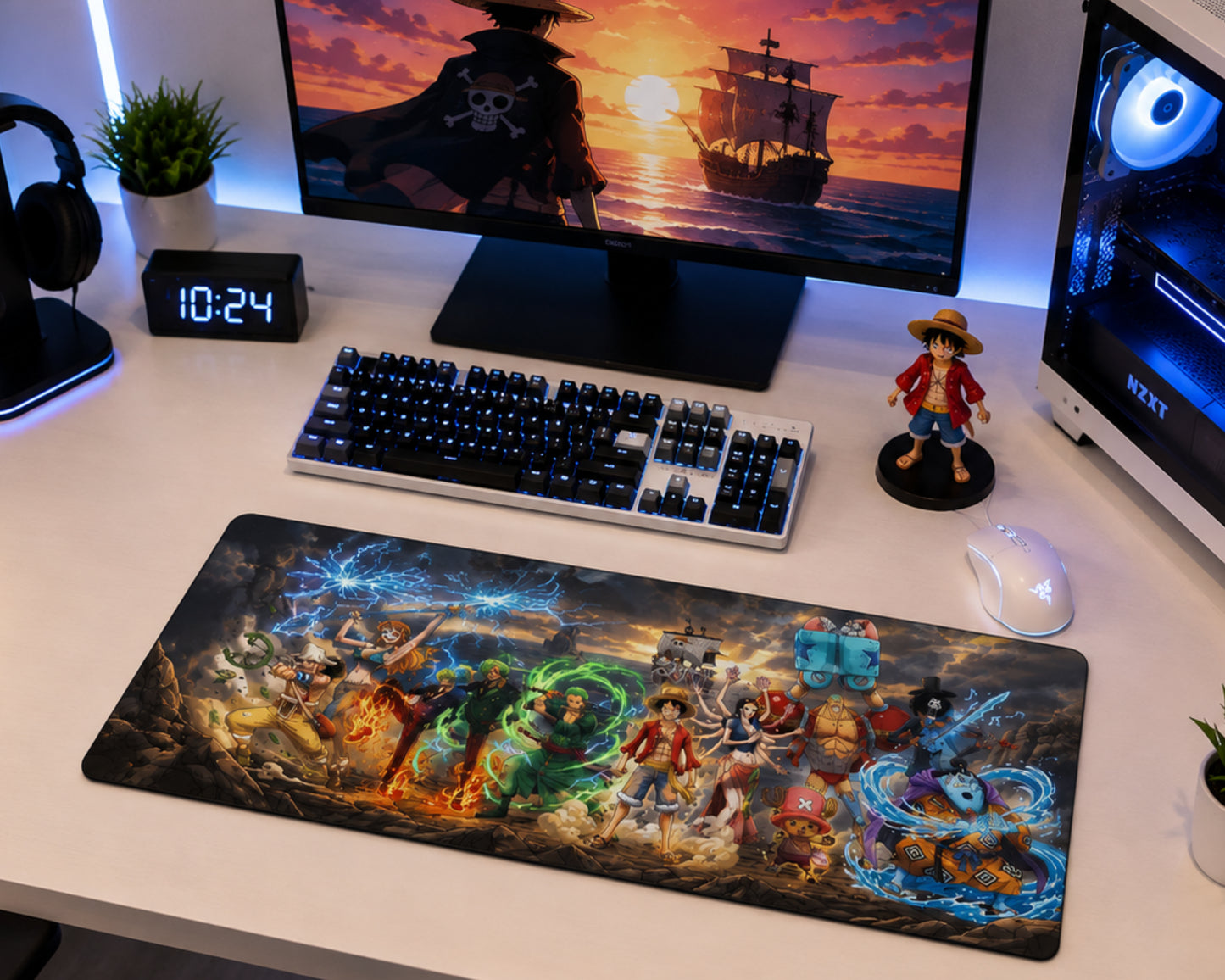 A large gaming desk mat featuring detailed anime artwork from One Piece, displayed on a white desk alongside a keyboard, mouse, monitor, and small figurine.