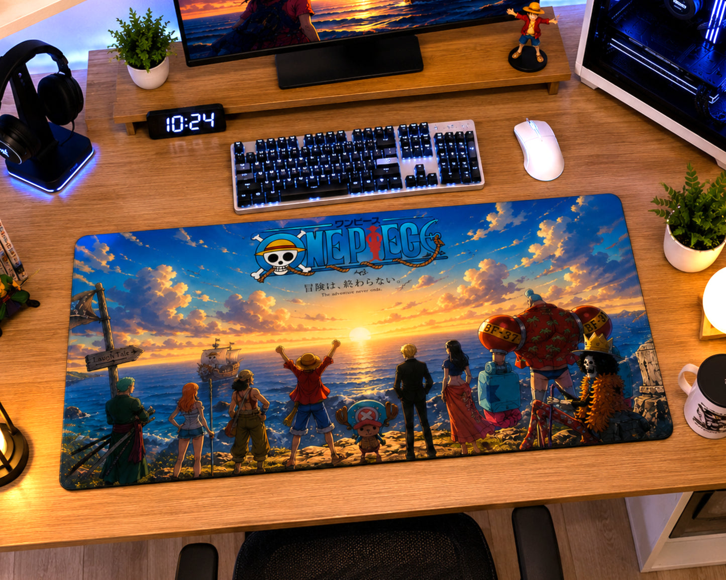 A large desk mat featuring the One Piece anime artwork with characters and the One Pica logo, displayed on a wooden desk in a gaming setup alongside a keyboard, mouse, headphones, and plants.