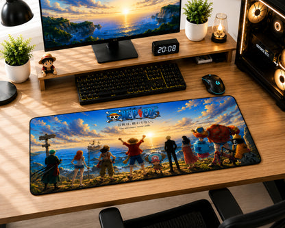 A large desk mat featuring characters and artwork from One Piece: Pirate Bay, displayed on a wooden desk in a gaming setup alongside a keyboard, mouse, monitor, and plants.