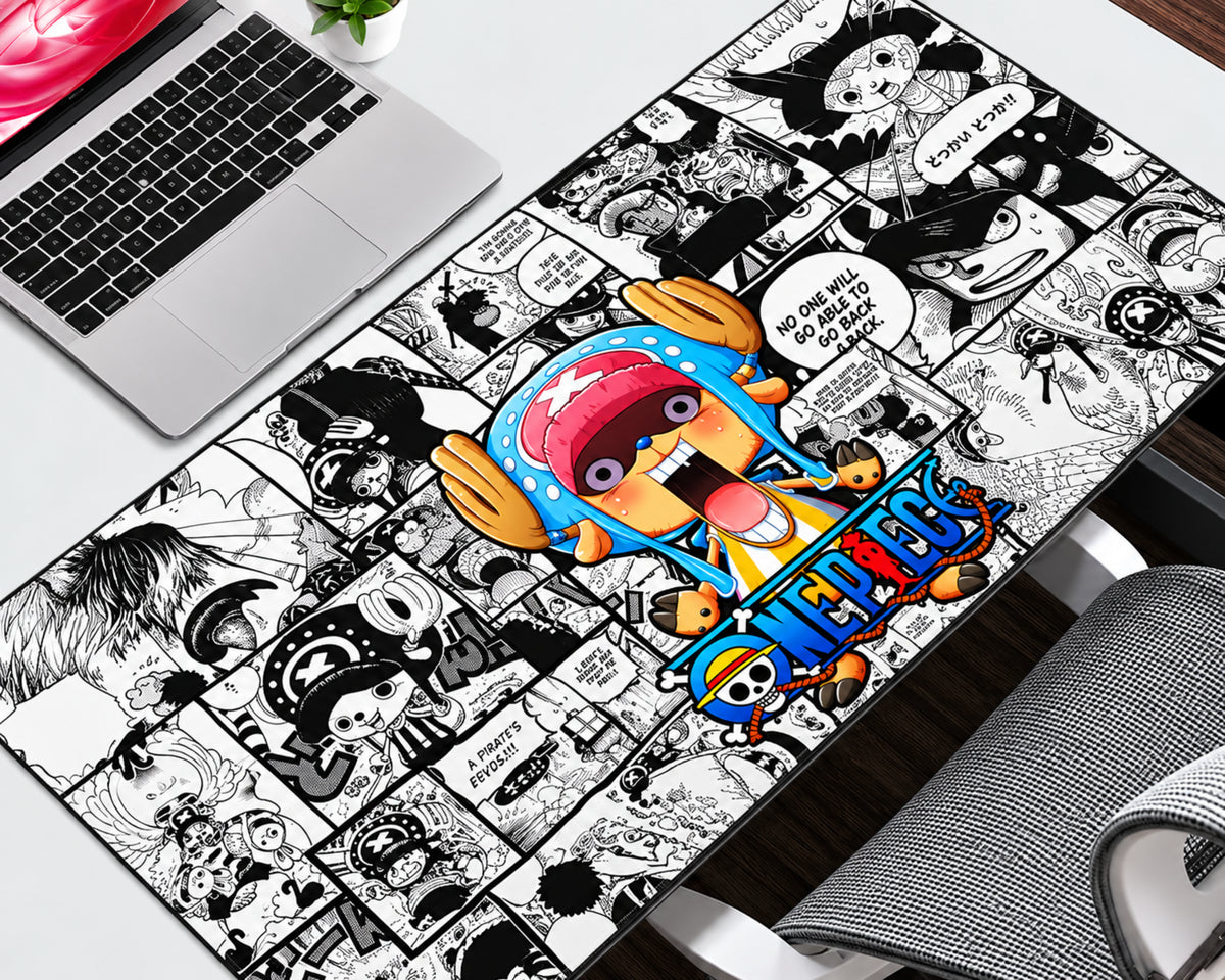 A large desk mat featuring a colorful One Piece anime character illustration over a black and white manga comic book panel background, displayed on a white desk next to a laptop.