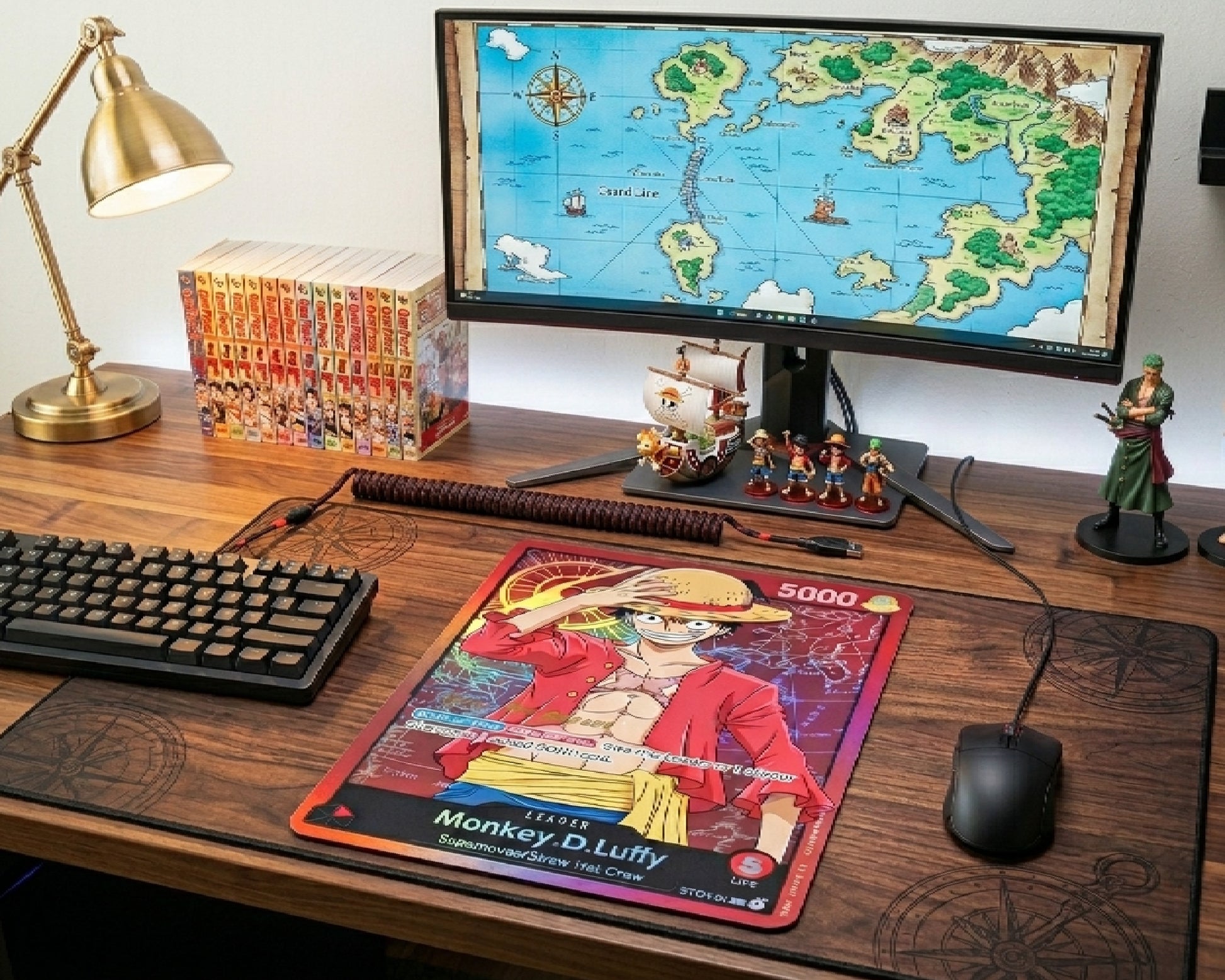 Monkey D. Luffy trading card inspired mouse pad on wooden gaming desk with mechanical keyboard, anime collectibles, One Piece manga collection, and nautical themed monitor wallpaper
